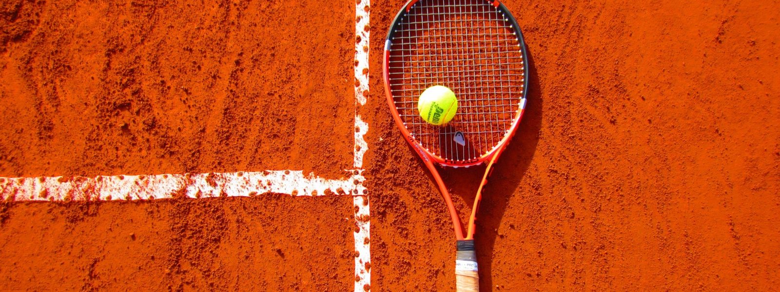 tennisracket en bal op gravel tennisbaan